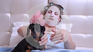 Man with cosmetic mask make massage dachshund, head and back