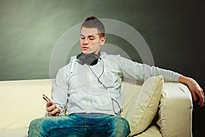 Man on couch with headphones smartphone