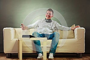 Man on couch with headphones smartphone and tablet