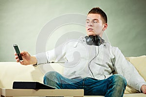 Man on couch with headphones smartphone and tablet