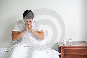 The man coughed and put his hand over his mouth and sat down on the bed