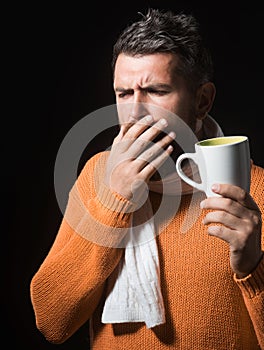 Man coughs. Sick male with cold or bronchitis coughing. Bearded handsome male in orange sweater wrapped in scarf with