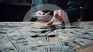 Man counting heap dollars at office desk close up. Calculating american money.