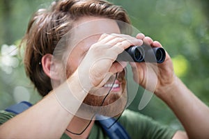 man in countryside looking through binoculars