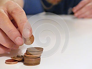 A man counts his coins on a table. Personal finance, savings, thrifty, or finance management