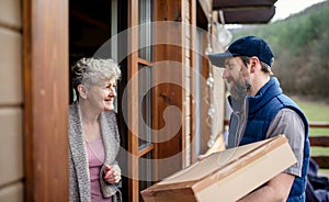 Man courier delivering parcel box to senior woman.