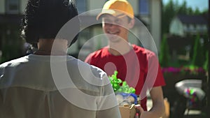 Man courier gives to woman customer box of fresh food during working day at delivery service spbd.