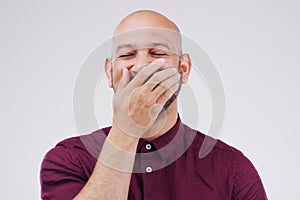 Man, cover mouth and laugh in studio for funny joke, comic and silly on gray background. Male person, happy and goofy