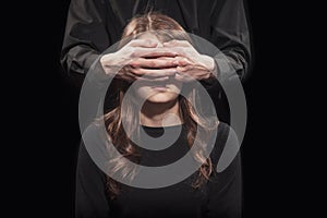 Man covered his eyes with a young woman on a black background