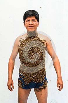 Man covered by many bees.