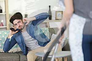 man covering ears while woman hoovering