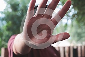 Man covering the face from the camera by his hand, the concept of secrecy and privacy