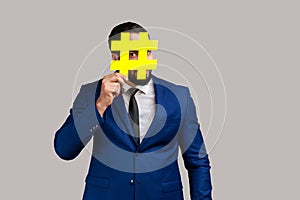 Man covering face with social media hashtag symbol, recommending to follow trendy content.