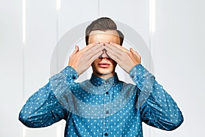 Man covering his face with hands in blue shirt