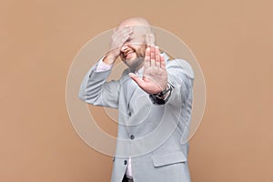 Man covering his face and showing stop hand gesture, sees something shameful.