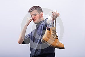 Man Covering His Nose While Holding Stinky Shoe