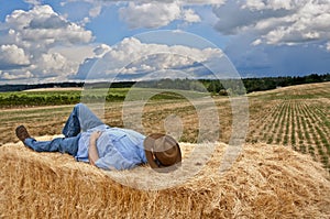 Man with cowboy hat on bale of hay