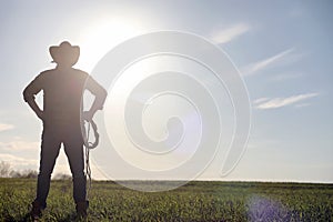 A man cowboy hat and a loso in the field. American farmer in a f