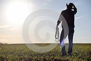 A man cowboy hat and a loso in the field. American farmer in a f