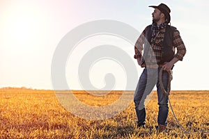 A man cowboy hat and a loso in the field. American farmer in a f