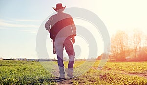 A man cowboy hat and a loso in the field. American farmer in a f