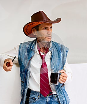 Man in cowboy hat with mug and pipe