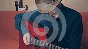 Man in cowboy hat plays red acoustic guitar