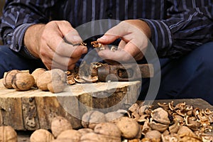 Man cracking walnuts with hammer at wooden table, closeup