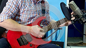 Man creative musician at studio works by playing,singing and recording guitar with notebook and microphone indoor in