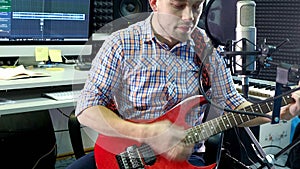 Man creative musician at studio works by playing,singing and recording guitar with notebook and microphone indoor in