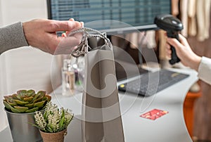 Man with credit card buying gift on Valentine`s Day in a female clothing store. Woman cashier, seller scanning using barcode