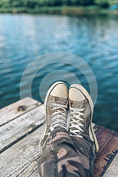 Man with crossed legs relaxing on riverbank pier