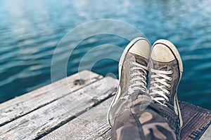 Man with crossed legs relaxing on riverbank pier