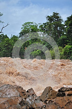 Man crosses the Khone Phapheng falls on the Mekong River in Laos on a rope during the Monsoon flooding