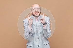 Man crossing fingers for luck, hope for better, ritual, looks up with hopeful look.