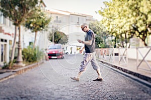 Man Crossing The Street Looking At His Phone