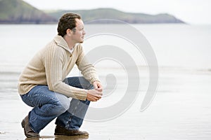 Man crouching on beach photo