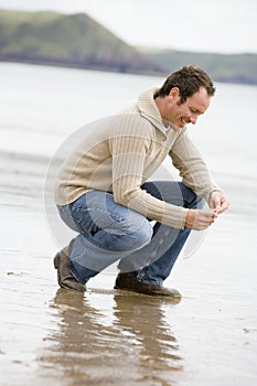 Man crouching on beach photo