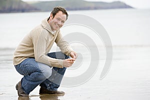 Man crouching on beach photo