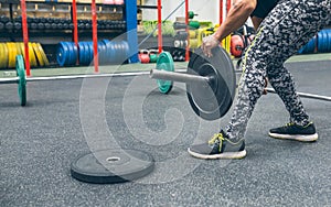 Man crouching changing the discs of the weightlifting bar