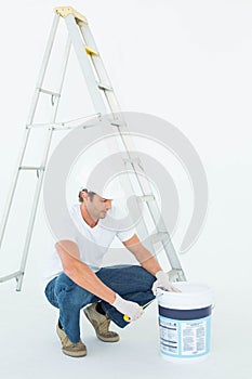 Man crouching while opening paint pot