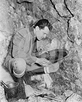Man crouching and panning for gold photo