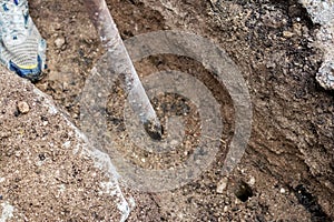 Man with a crowbar crushes hard soil while digging a ditch on a construction site