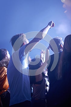 Man in crowd, fans and dancing at concert, music festival and hands in air for energy or night event. Dance, fun or