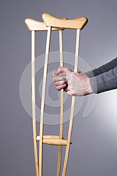 Man with crutches on a gray background