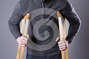 Man on crutches on a gray background