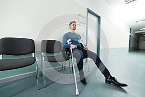 Man with crutches sitting on chair