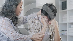 Man crying and being comforted by loving mature mother. Support, care, trust and sympathy concept