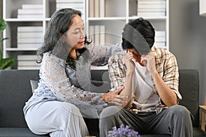 Man crying and being comforted by loving mature mother. Support, care, trust and sympathy concept.