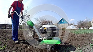 Man cultivates the ground in the garden with a tiller, preparing the soil for sowing